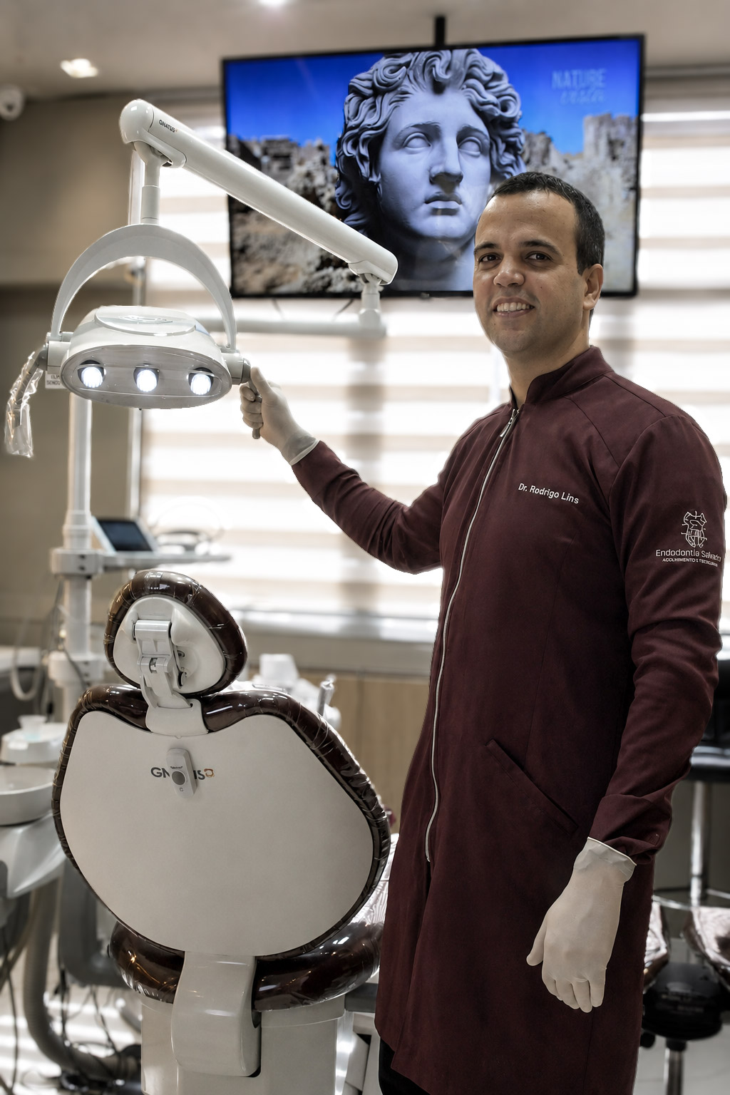 Dr. Rodrigo ao lado da cadeira odontológica